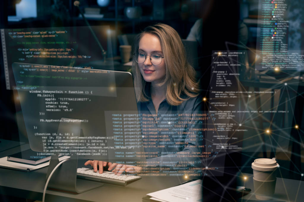 Woman works at computer, screen shows program code